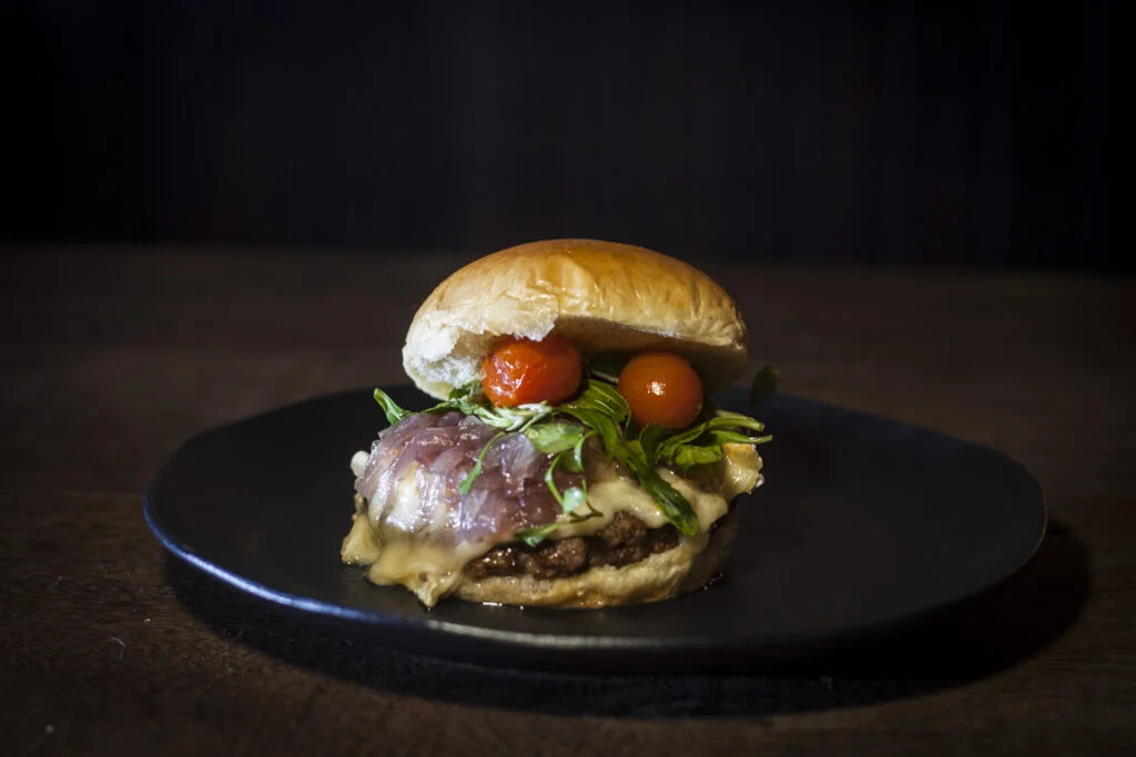 Hambúrguer com folhas e tomate servido em prato escuro